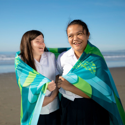 Two girls with Ko Taku Reo flag around shoulders
