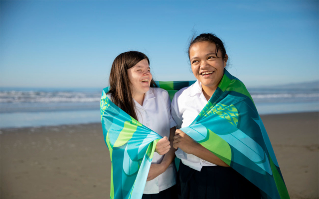 Two girls with Ko Taku Reo flag around shoulders